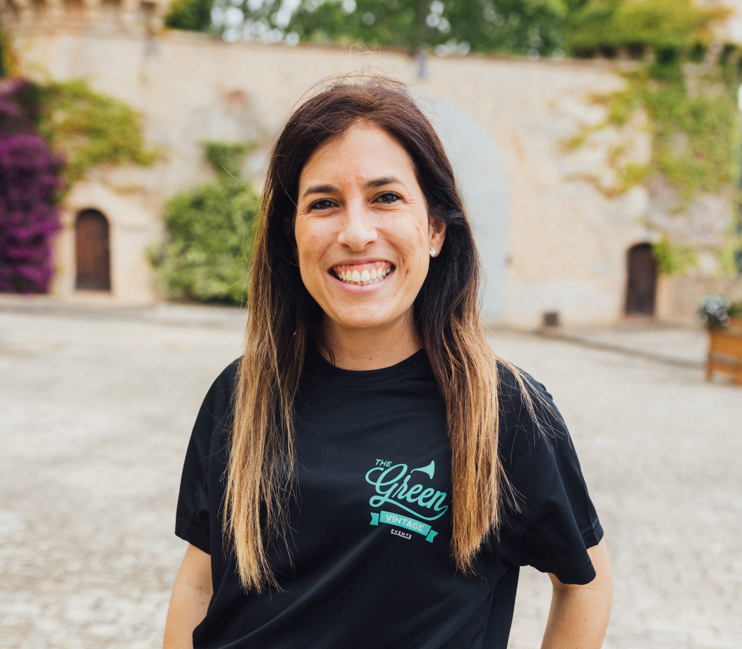 mujer del mundo de los eventos sonriendo en un lugar con arboles 